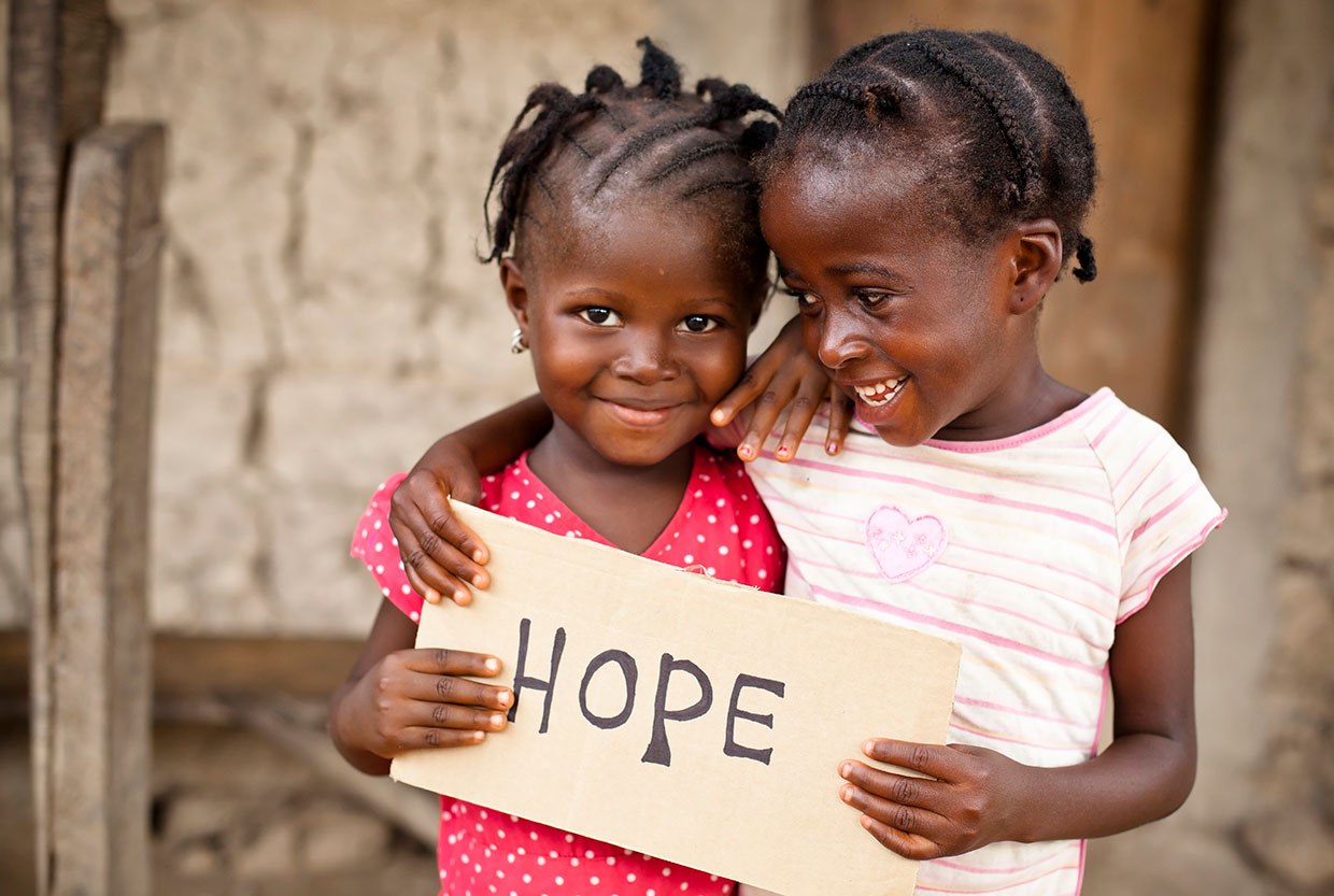2 young African girls holding a sign that reads, hope